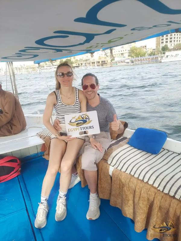 Happy clients holding an Egypt 1 Tours banner during a private sunset felucca ride on the Nile in Luxor