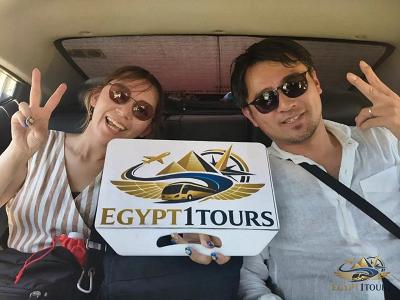 Happy clients smiling inside modern van holding Egypt 1 Tours welcome sign for transfer to Hurghada